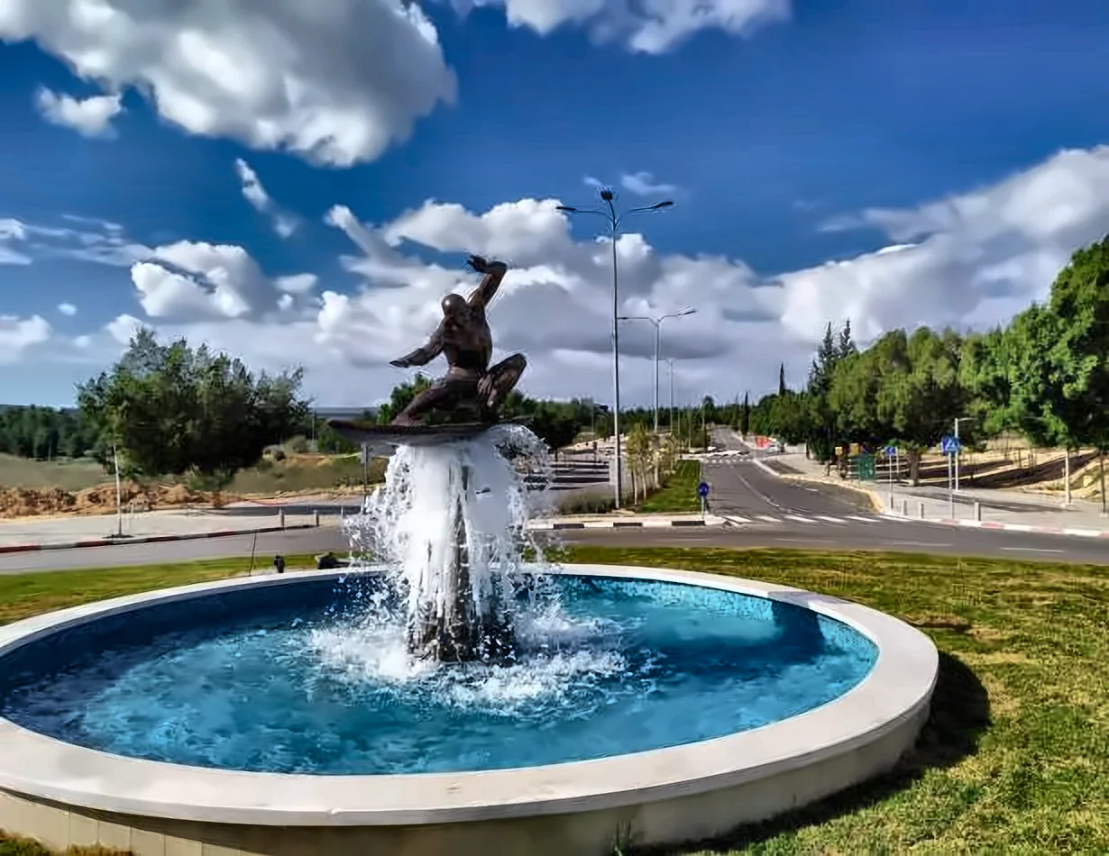 מזרקת הגולש המרחף: גולש מברונזה על גלשן מעל סילון מים, בבריכה עגולה בכיכר במודיעין