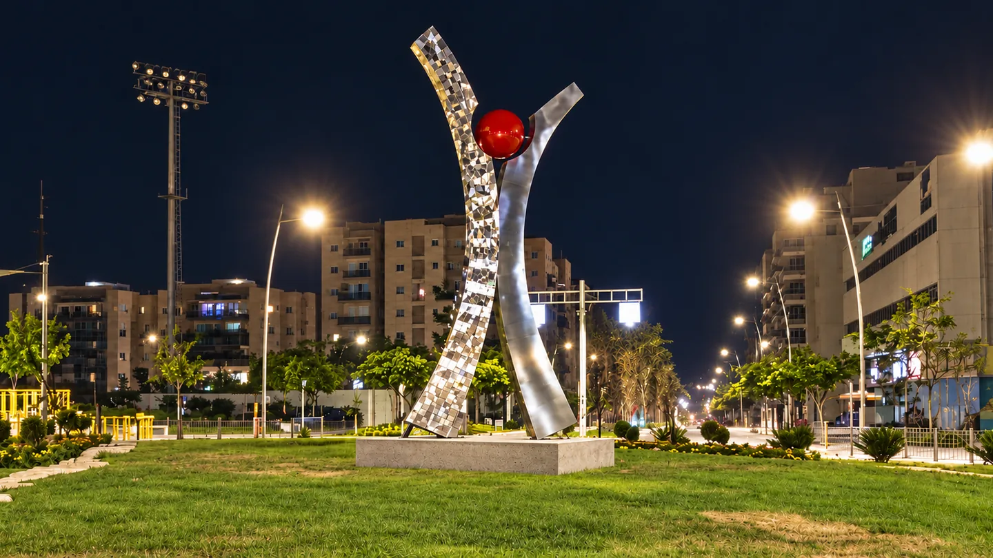 שער המערב: שתי להבות נירוסטה בגובה 5.5 מטר, אחת בפסיפס מלוטש ואחת מוברשת, נפגשות סביב כדור אדום, בכניסה לשכונת מערב בנתיבות, בלילה